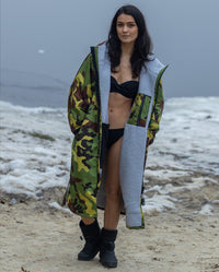 Woman stood in front of lake, wearing bikini and Camo Grey dryrobe® Advance Long Sleeve on top 