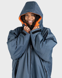 Woman wearing dryrobe Advance Long Sleeve change poncho in Dark Grey Orange with hood up 