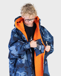 Boy wearing dryrobe Advance Long Sleeve Changing poncho in Blue Camo Orange, opening internal pocket 