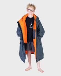 Boy wearing dryrobe Advance Long Sleeve Change poncho in Dark Grey Orange unzipped 