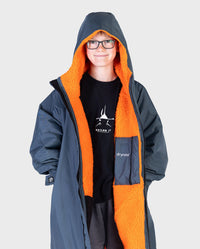 Boy wearing dryrobe Advance Long Sleeve Change poncho in Dark Grey Orange unzipped with hood up