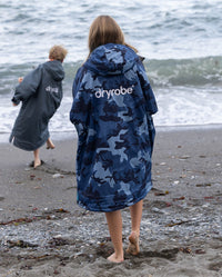 Kids playing by the sea on a beach, wearing Girl wearing dryrobe Advance Long Sleeve Changing ponchos