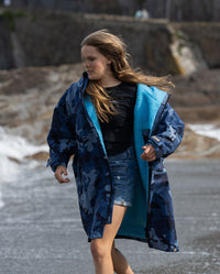 Girl running along the beach, wearing dryrobe Advance Long Sleeve Changing poncho in Blue Camo Blue