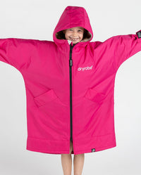 Girl holding arms out wearing dryrobe Advance Long Sleeve Changing poncho in Pink Light Grey with hood up