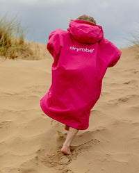 Girl running up sand dune wearing dryrobe Advance Long Sleeve Changing robe in Pink Light Grey 