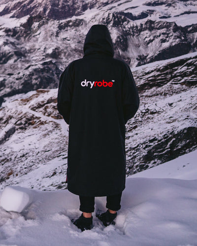 *MALE* Man with stood in front of snowy mountains with back to camera, wearing dryrobe Advance Long Sleeve changing robe in Black Red 