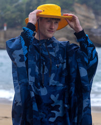 *MALE* Man wearing dryrobe Quick Dry Brimmed Hat and dryrobe® Waterproof Poncho, in the rain on the beach