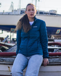 Woman sat on edge of boat, wearing dryrobe Mid-layer Jacket in Deep Sea Blue