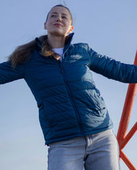 Woman smiling with blue sky behind her, wearing dryrobe Mid-layer Jacket in Deep Sea Blue