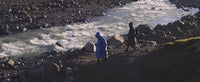 Two people walking alongside a river, wearing dryrobe® Advance