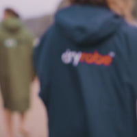 Group of adults walking across a beach, in swimming gear and dryrobe® Advance’s
