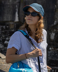 Woman stood in the sun next to a wall, wearing Deep Sea Blue dryrobe Quick Dry Cap