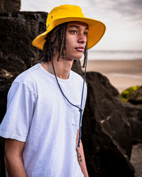 *MALE* Man stood in front of rocks and sea wearing dryrobe Quick Dry Brimmed Hat in Yellow