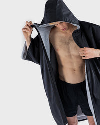 1|Man wearing Black Grey dryrobe® Advance Short Sleeve with hood up, unzipped