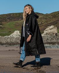 1|Woman walking on a beach, wearing Black Grey dryrobe® Advance Short Sleeve