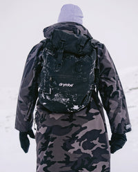 Person walking away from camera in the snow, wearing  dryrobe® Eco Compression Backpack