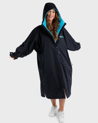 1|Woman wearing Black Blue dryrobe® Advance Long Sleeve with hood up
