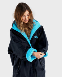 1|Woman pulling down sleeve on Black Blue dryrobe® Advance Long Sleeve