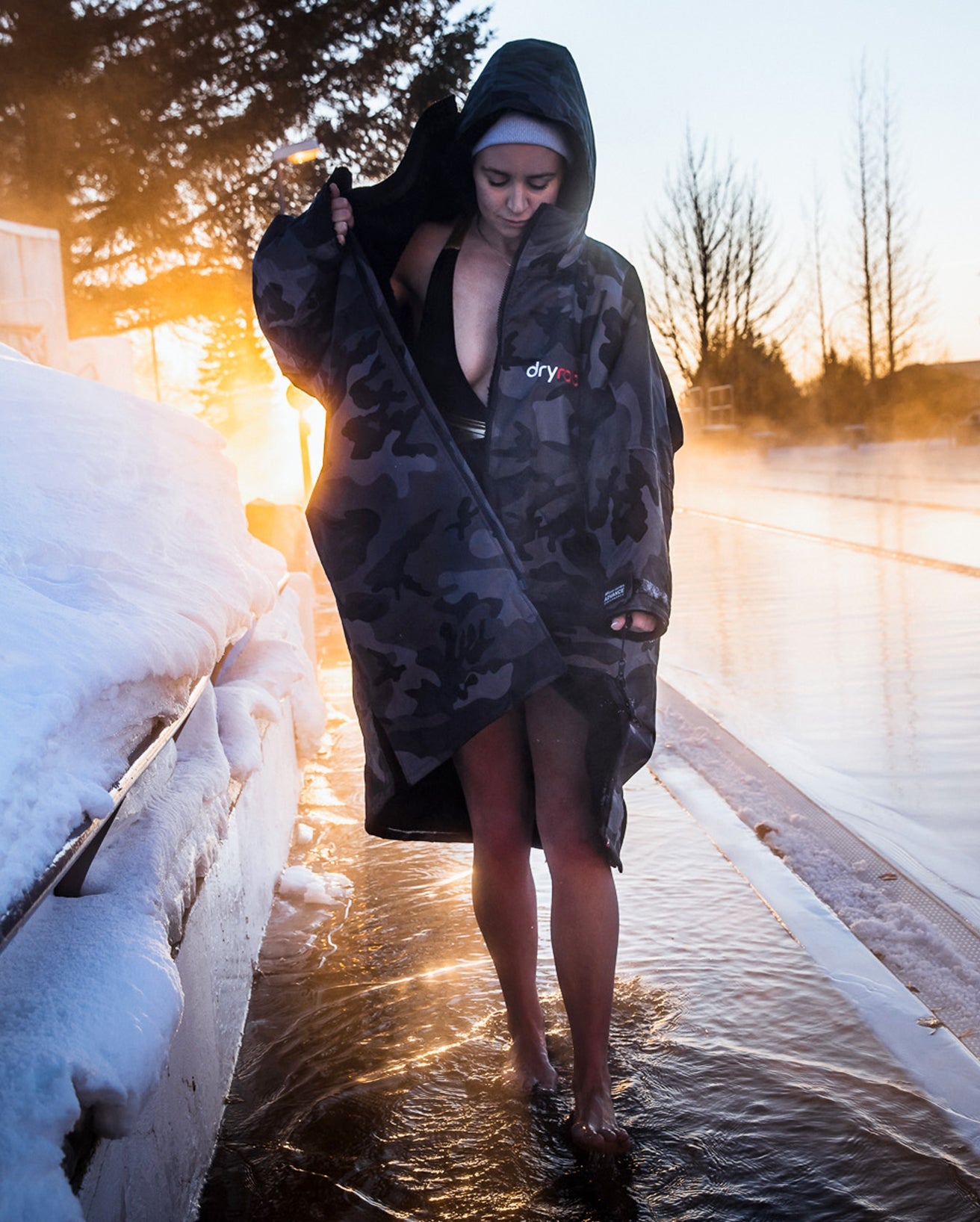 Woman stood by icy pool, zipping up Black Camo dryrobe® Advance Long Sleeve