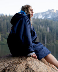 1|Woman sat by a lake on a rock, wearing  Navy Grey dryrobe® Advance Long Sleeve