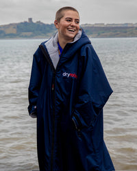 1|Woman stood in front of the sea, wearing  Navy Grey dryrobe® Advance Long Sleeve
