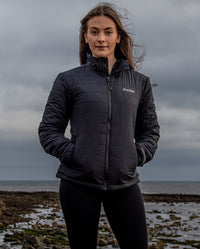 Woman stood on a beach, wearing dryrobe® Mid-Layer Jacket