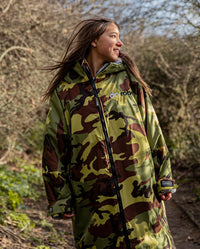 1|Girl stood smiling in front of trees, wearing Camo Grey dryrobe® Advance Kids Long Sleeve