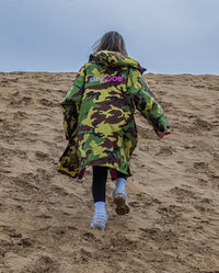 1|Girl walking up sand dune wearing Camo Pink dryrobe® Advance Kids Long Sleeve