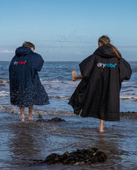 1|Two kids splashing in the shoreline, wearing dryrobe® Advance Kids Long Sleeve