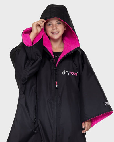 Girl wearing Black Pink dryrobe® Advance Kids Short Sleeve change poncho with hood up