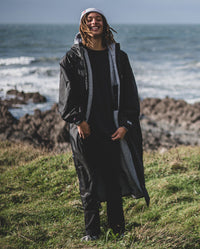 *MALE* stood in front of the sea, wearing Grey dryrobe® Eco Beanie and Black Grey dryrobe® Advance Long Sleeve