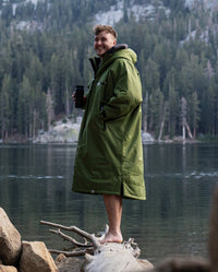 *MALE* stood on fallen tree in front of lake and mountains, wearing Forest Green dryrobe® Advance Long Sleeve