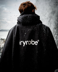 *MALE* stood in the rain with back to the camera, wearing Black dryrobe® Waterproof Poncho 